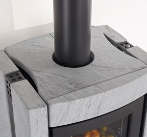 The image shows a section of an elegant wood-burning stove. The focus is on the top cover, which is made of gray stone. This robust stone surface gives the stove a modern and stylish look. The black smoke vent contrasts sharply with the light-colored stone. This wood-burning stove is ideal for modern living spaces where design and functionality are key.