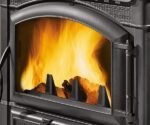 Das Bild zeigt einen detaillierten Ausschnitt eines Kaminofens, der den Fokus auf die robuste Frontscheibe legt. Hinter der klaren Glasoberfläche lodern lebhafte Flammen und sorgen für eine warme, einladende Atmosphäre. Der elegante Rahmen des Ofens betont die hochwertige Verarbeitung. Perfekt geeignet für alle, die nach einem stilvollen Holzofen für ihr Zuhause suchen.