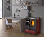 The picture shows a stylish wood-burning stove in a modern living area. The stove has red cladding and is equipped with several doors. One of the doors provides a view of the flickering fire, creating a warm and inviting atmosphere. The stove stands next to a dining table with two chairs, on which there is a bottle of wine and glasses. The room's furnishings are elegant and cozy, and the wood-burning stove blends harmoniously into the ambience, ideal for anyone looking for an efficient and attractive wood stove.