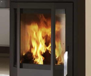 The picture shows a modern stove in the color black with a large glass pane that allows a view of the lively fire inside. The flames dance behind the clear pane, which is part of a detailed section of the stove. This steel design exudes elegance and warmth and is an appealing addition to any living space. The focus is on the glass of the stove, which impressively reflects the blazing fire.