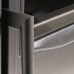 De afbeelding toont een detail van een houtkachel, waarbij de focus ligt op de deur. De afgebeelde deur van de houtkachel is gemaakt van robuust materiaal, wat wijst op een hoge kwaliteit en duurzaamheid. De focus ligt op de strakke lijnen en de solide afwerking, waardoor de houtkachel er esthetisch en functioneel uitziet. Dit zou een positieve bijdrage kunnen leveren aan de sfeer in huis.