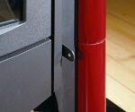 Detail van een houtkachel met focus op de regelaar. De houtkachel heeft een elegante mix van zwart metaal en een glanzend rood element. De regelaar is subtiel geïntegreerd en draagt bij aan de moderne esthetiek van de kachel. Ideaal voor iedereen die waarde hecht aan stijlvolle bedieningsmogelijkheden voor zijn houtkachel.