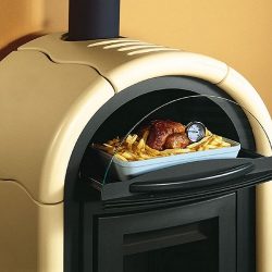 Alt-tekst: De afbeelding toont een detail van een houtkachel met de nadruk op het bakvak. De crèmekleurige houtkachel heeft een stijlvol, gebogen ontwerp. In het bakvak bevindt zich een braadstuk in een ovenschaal, vergezeld van frietjes en een thermometer om de temperatuur te controleren. De houtkachel combineert design en functionaliteit in een aantrekkelijk element voor elk huis.