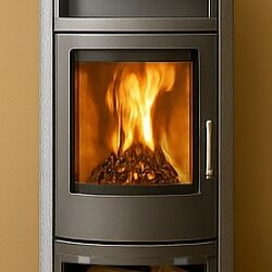 A stove with a large pane of glass, behind which a lively fire burns, on a light brown background.