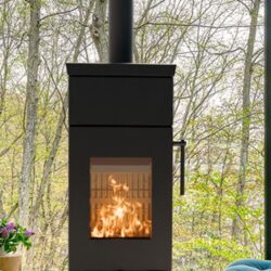 Moderner schwarzer Kaminofen mit großen Glastüren, durch die Flammen sichtbar sind, im Vordergrund eines Waldhintergrundes.