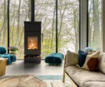 Moderner Kaminofen in einem gemütlichen Wohnzimmer mit großen Fenstern und grüner Aussicht.