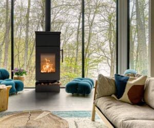 Moderner Kaminofen in einem gemütlichen Wohnzimmer mit großen Fenstern und grüner Aussicht.
