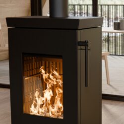Feuer im Kaminofen Thermorossi Zen W, Fokus auf die Glasscheibe mit Blick auf die Flammen. Moderner Innenraum im Hintergrund.